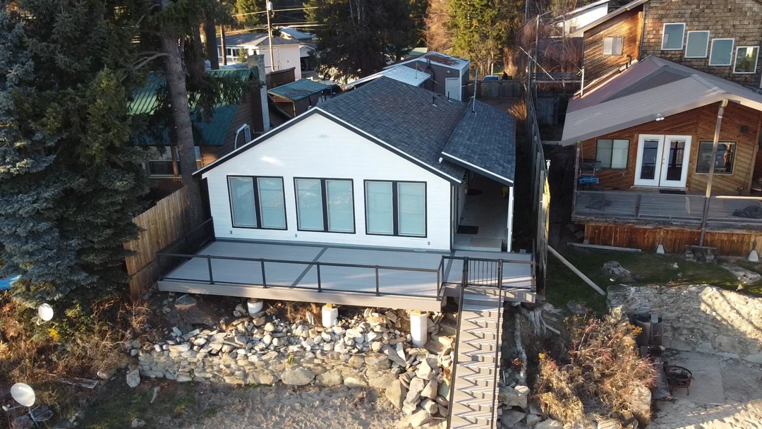 Gray deck with stairs and glass railing.