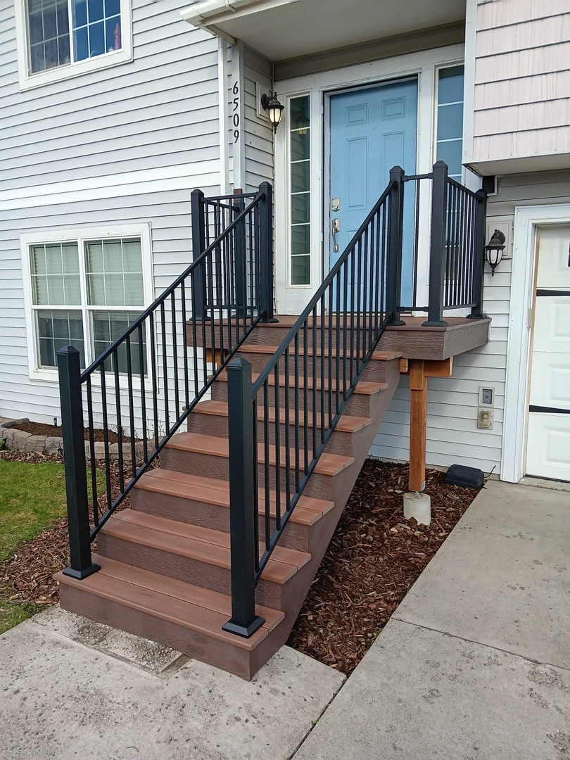 Brown deck with black railing and stairs.