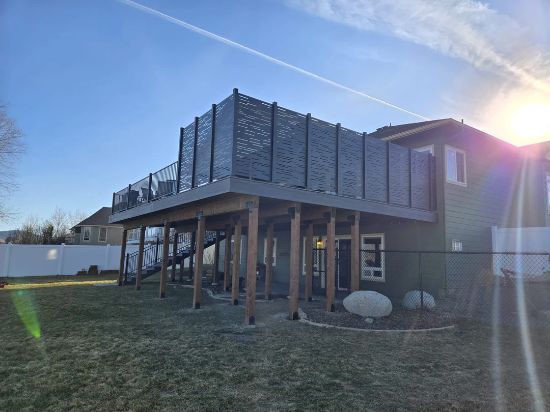 Deck with stairs leading up to it and railing plus privacy walls.