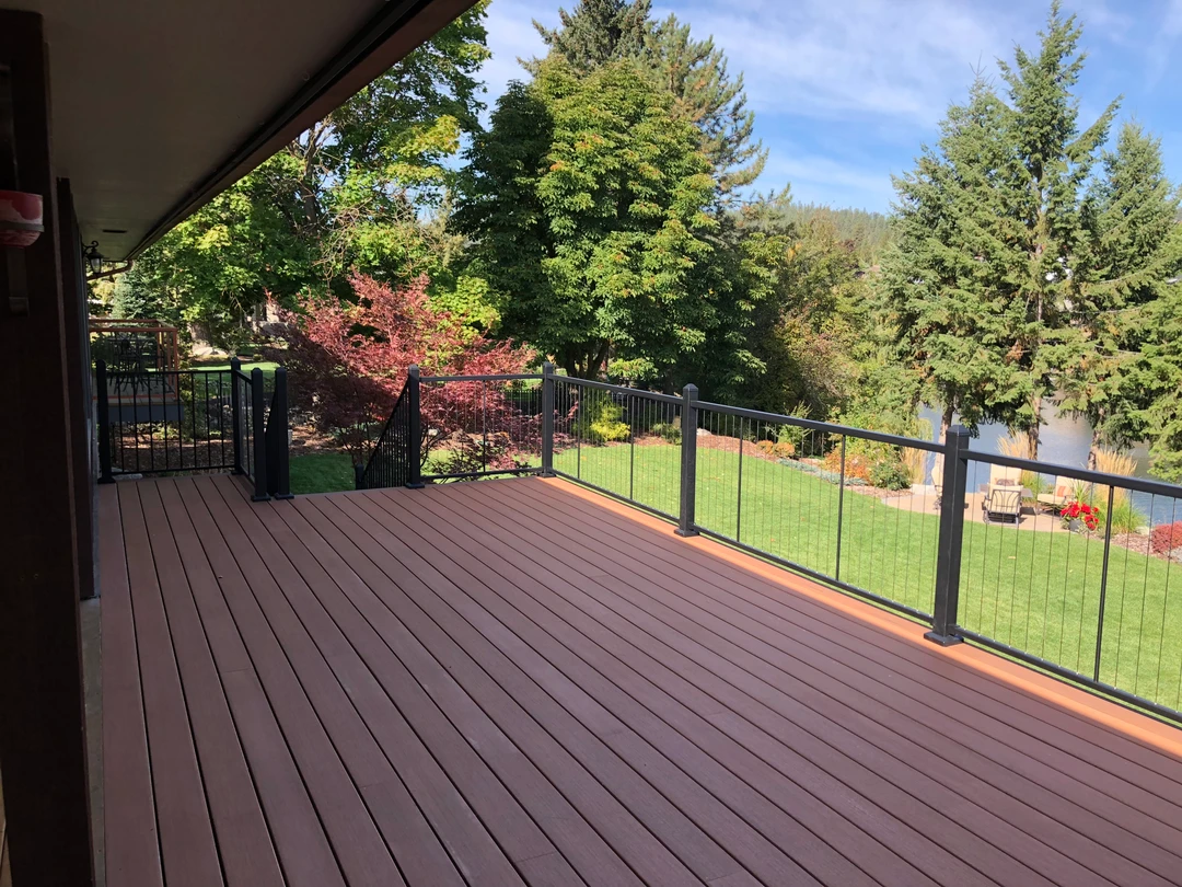 Brown deck with black vertical picket railing.