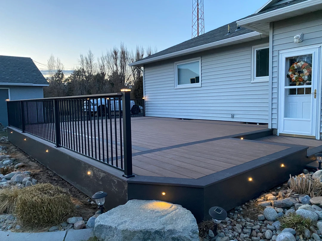 Brown deck with black railing and yellow lights.