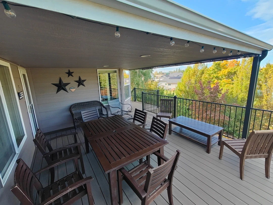 Gray furnished deck with black railing.