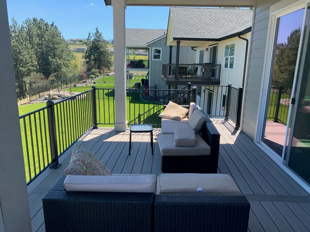 Gray deck with black railing and furniture.