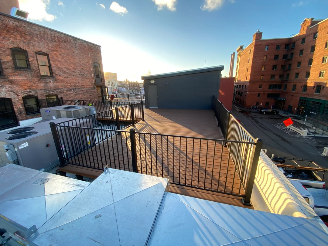 Deck in the city with black railing.