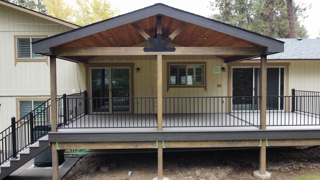 Open beam style cover stained. New wood cover built over deck. Natural wood cover. Exposed wood cover with lighting installed the ceiling and a fan. 